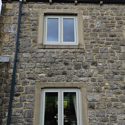 A cat sitting on a window sill in a stone building.