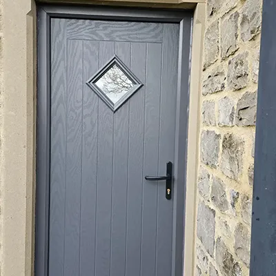 A grey front door with a brick wall.