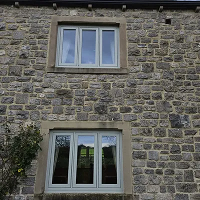 A stone building with two windows and a clock.