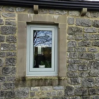 A brick building with a window and a cat sitting in the window.