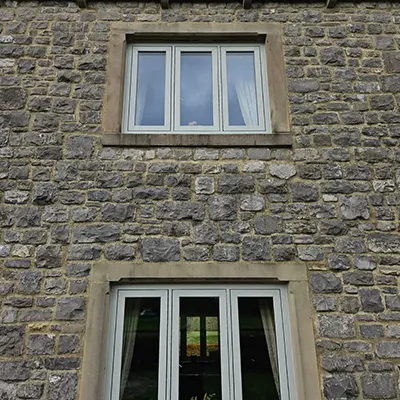 A cat sitting in a window of a stone building.