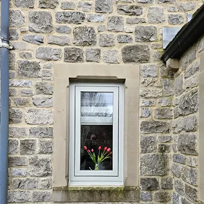 A cat sitting on a window sill in front of a brick building.