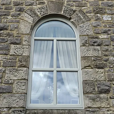 A window with a curtain and a clock on the side of it.