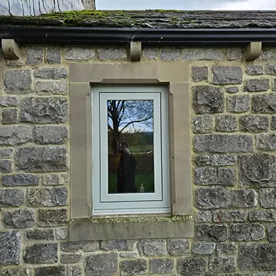 A cat sitting on a window sill in front of a brick building.
