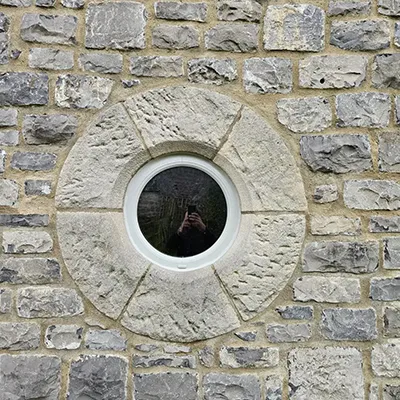 A person taking a picture of themselves through a round window.