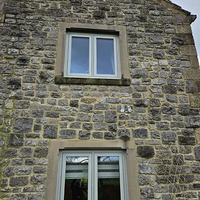 A cat sitting in the window of a stone building.