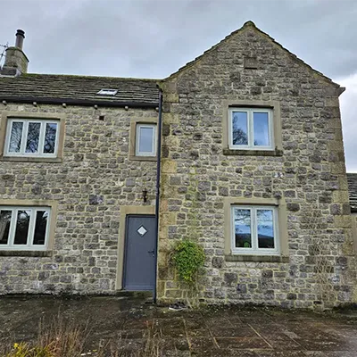 A stone building with a blue door and windows.