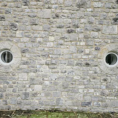 A red fire hydrant sitting in front of a brick wall.