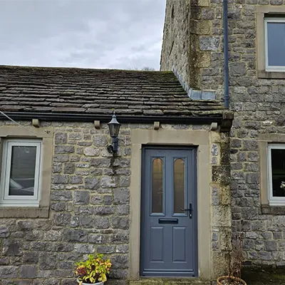 A stone building with a blue door and windows.